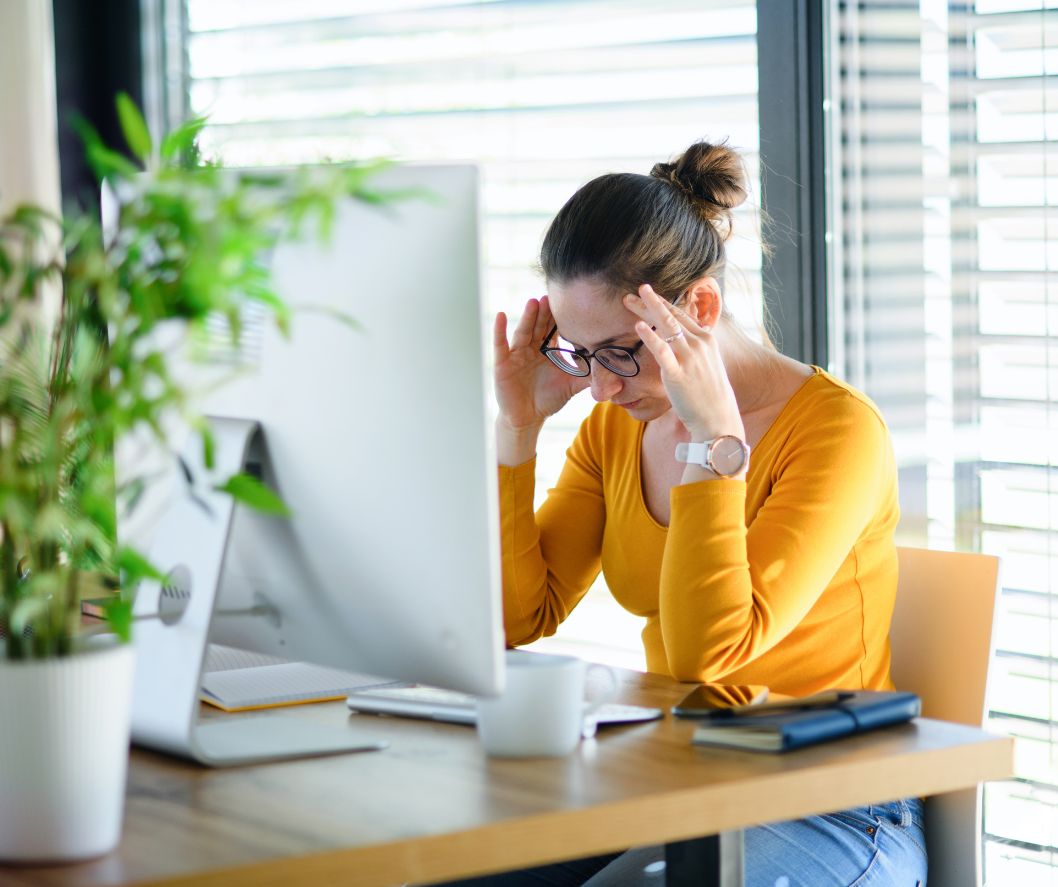 Autistic woman yellow top sitting at desk looking stressed